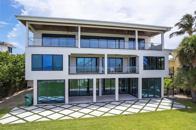 rear view of property featuring ceiling fan, a yard, a balcony, and a patio