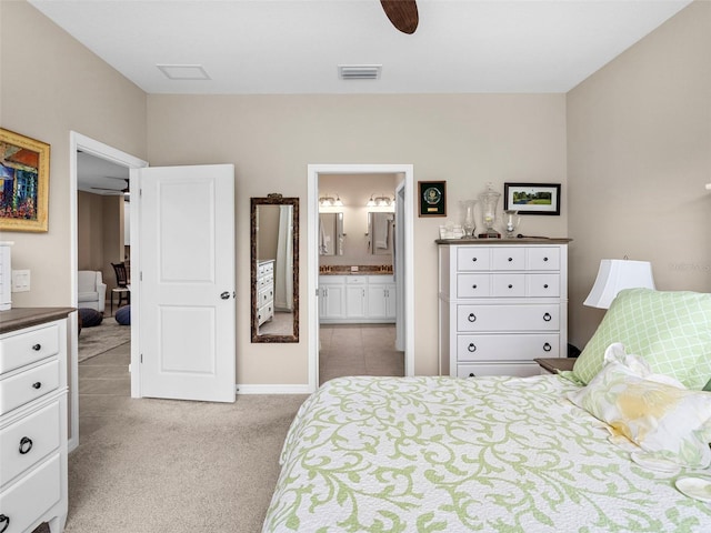 bedroom featuring ceiling fan, light colored carpet, and ensuite bath