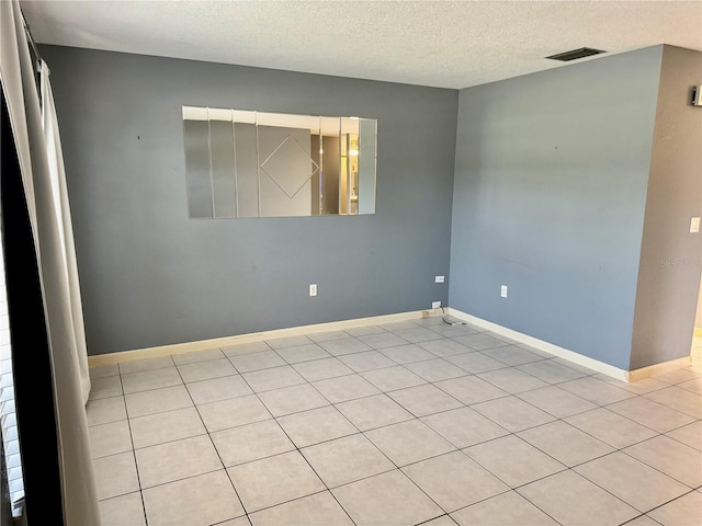 spare room featuring light tile patterned flooring and a textured ceiling