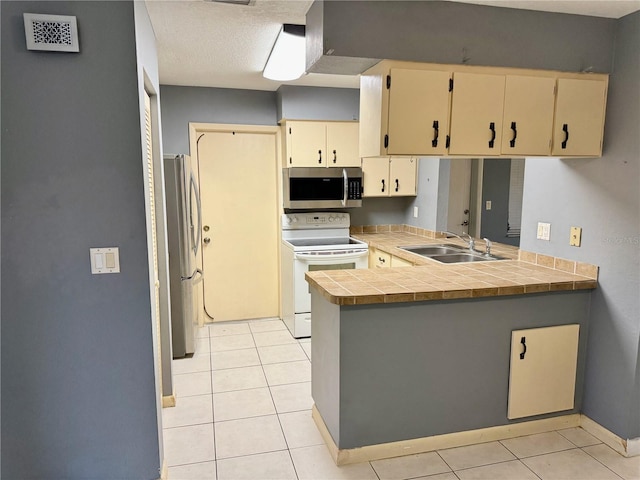 kitchen featuring light tile patterned floors, appliances with stainless steel finishes, sink, and kitchen peninsula