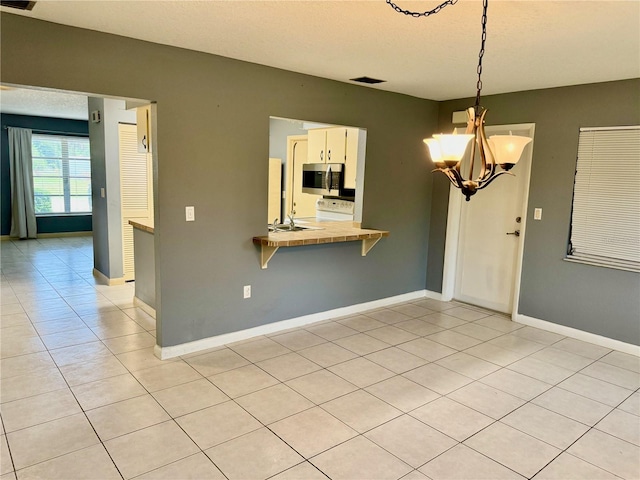 tiled empty room featuring a chandelier