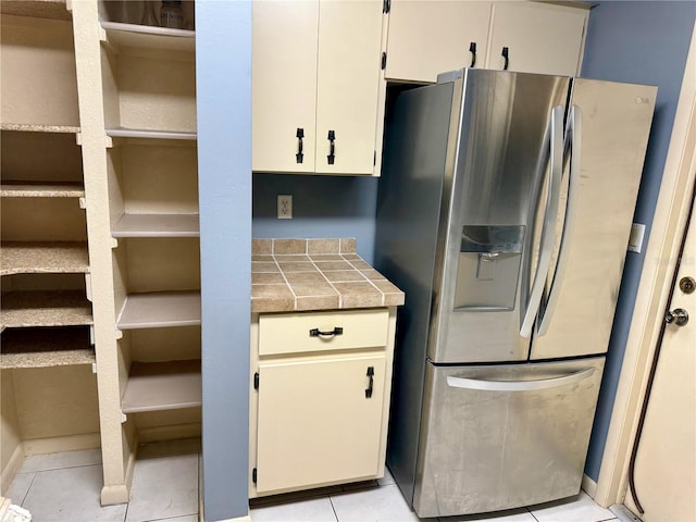 kitchen featuring white cabinets, stainless steel refrigerator with ice dispenser, tile countertops, and light tile patterned floors