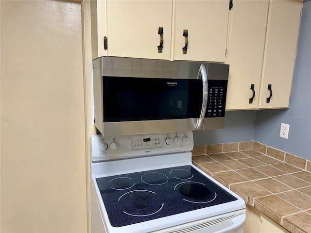 details featuring white cabinetry, white electric stove, and tile countertops