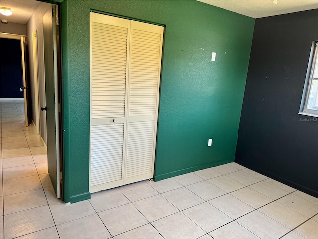 unfurnished bedroom featuring light tile patterned flooring and a closet