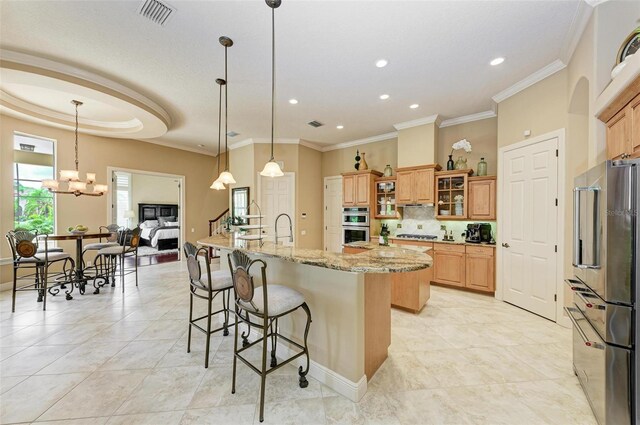 kitchen featuring a kitchen bar, tasteful backsplash, light stone counters, decorative light fixtures, and crown molding