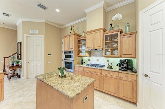 kitchen featuring crown molding, light tile patterned floors, a kitchen island, appliances with stainless steel finishes, and decorative backsplash