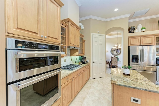 kitchen with a notable chandelier, crown molding, light stone countertops, appliances with stainless steel finishes, and light tile patterned floors