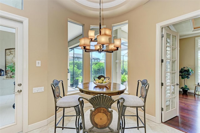 dining area featuring a notable chandelier, wood-type flooring, french doors, and a raised ceiling