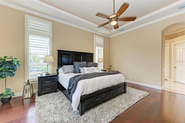 bedroom featuring a tray ceiling, dark hardwood / wood-style flooring, ceiling fan, and crown molding