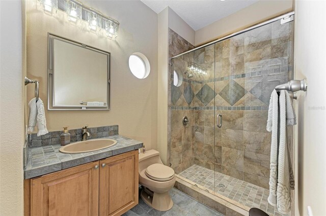 bathroom featuring tile patterned flooring, a shower with door, toilet, and vanity