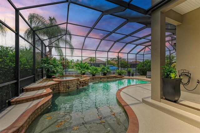 pool at dusk featuring a patio, an in ground hot tub, and a lanai