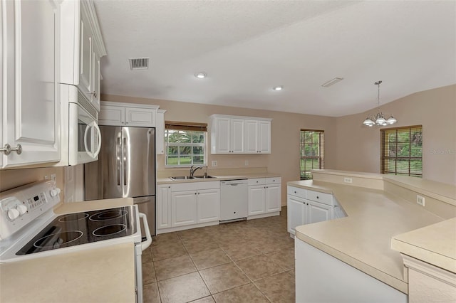 kitchen with white appliances, decorative light fixtures, white cabinetry, sink, and vaulted ceiling