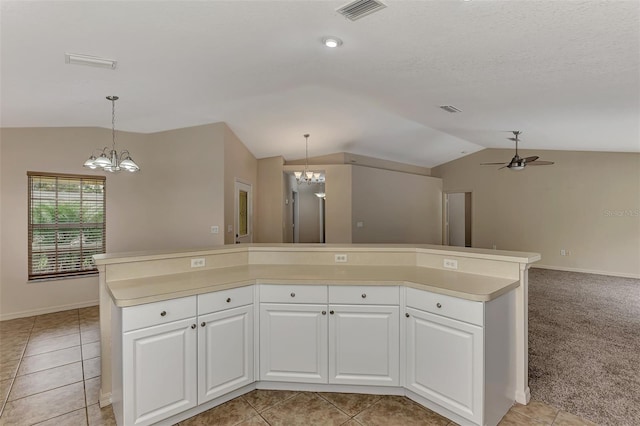 kitchen featuring light tile patterned floors, lofted ceiling, hanging light fixtures, a kitchen island, and white cabinets