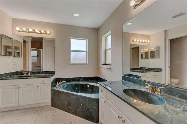 bathroom featuring a relaxing tiled tub, tile patterned floors, vanity, and toilet