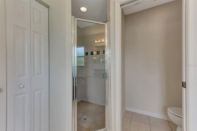 bathroom featuring toilet, tile patterned flooring, and an enclosed shower