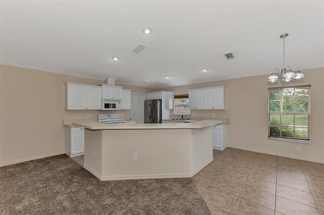 kitchen with decorative light fixtures, white appliances, white cabinetry, and a kitchen island