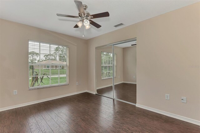 unfurnished bedroom with ceiling fan, dark wood-type flooring, and a closet