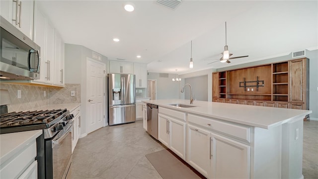 kitchen with ceiling fan, stainless steel appliances, a kitchen island with sink, white cabinets, and sink