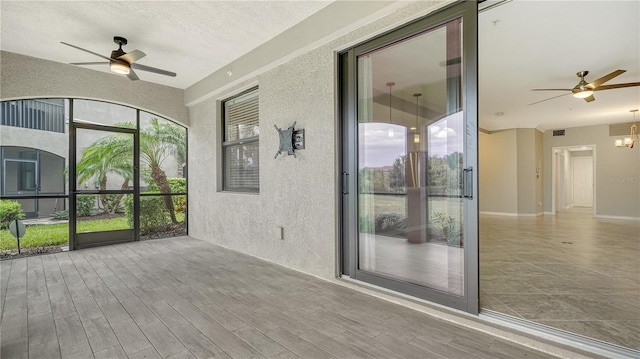 unfurnished sunroom featuring ceiling fan with notable chandelier