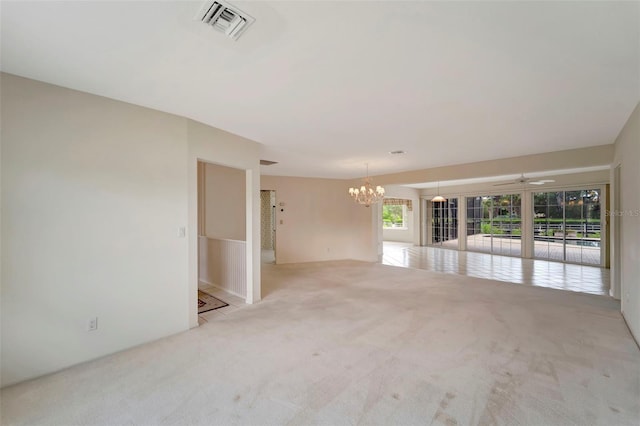 carpeted empty room with ceiling fan with notable chandelier