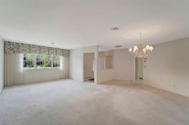 empty room featuring light colored carpet and a notable chandelier