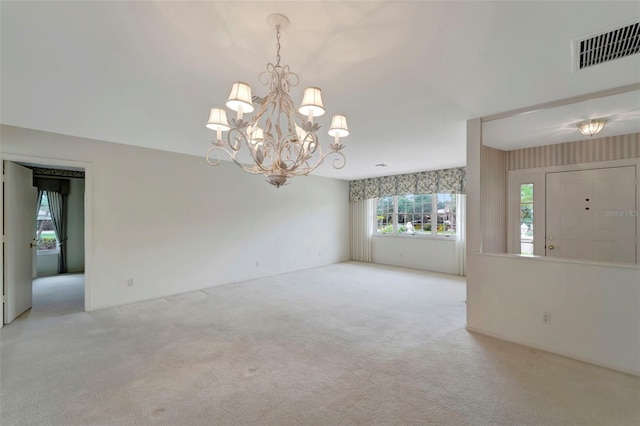 spare room featuring an inviting chandelier and light colored carpet