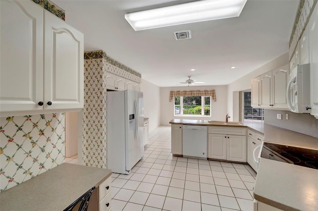 kitchen with light tile patterned floors, white cabinets, white appliances, and kitchen peninsula