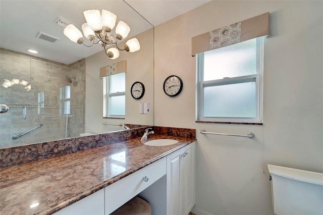 bathroom with a shower with door, vanity, a chandelier, and toilet