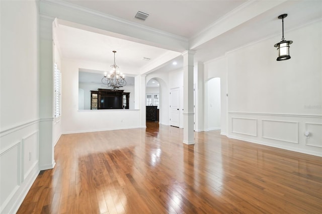 unfurnished living room featuring crown molding, wood-type flooring, and an inviting chandelier