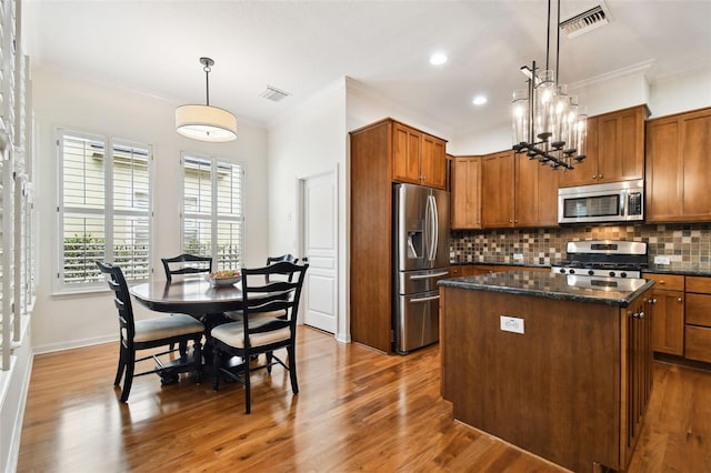 kitchen with crown molding, pendant lighting, a center island, and stainless steel appliances