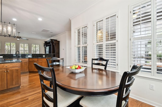 dining area featuring ceiling fan, crown molding, light hardwood / wood-style floors, and sink