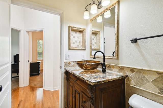 bathroom featuring vanity, wood-type flooring, tile walls, and toilet