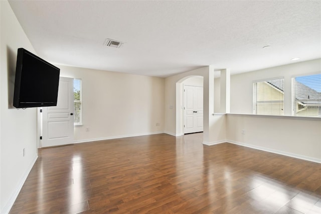 unfurnished living room featuring a textured ceiling and dark hardwood / wood-style flooring