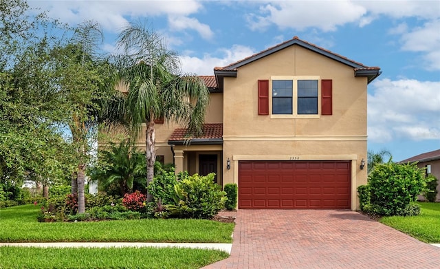 view of front facade featuring an attached garage, stucco siding, a front lawn, a tiled roof, and decorative driveway