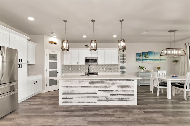 kitchen featuring appliances with stainless steel finishes, white cabinets, light countertops, and decorative light fixtures