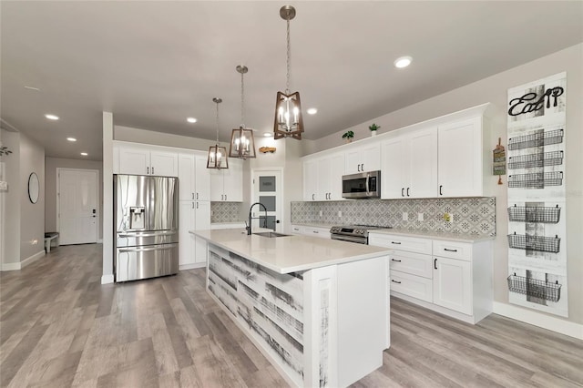 kitchen featuring pendant lighting, stainless steel appliances, light countertops, white cabinets, and a sink