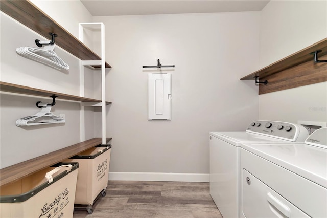 laundry room with laundry area, electric panel, baseboards, wood finished floors, and independent washer and dryer