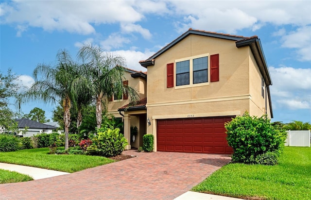 view of front facade featuring stucco siding, an attached garage, decorative driveway, and a front lawn