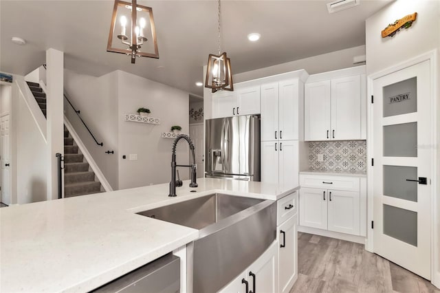 2352 Marton Oak Blvd, North Port, FL 34289 - kitchen with stainless steel appliances, a sink, hanging light fixtures, white cabinetry, and light wood-style floors