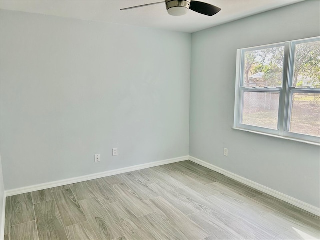 spare room with a ceiling fan, light wood-type flooring, and baseboards