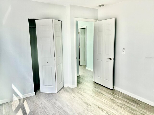 unfurnished bedroom with light wood finished floors, visible vents, and baseboards