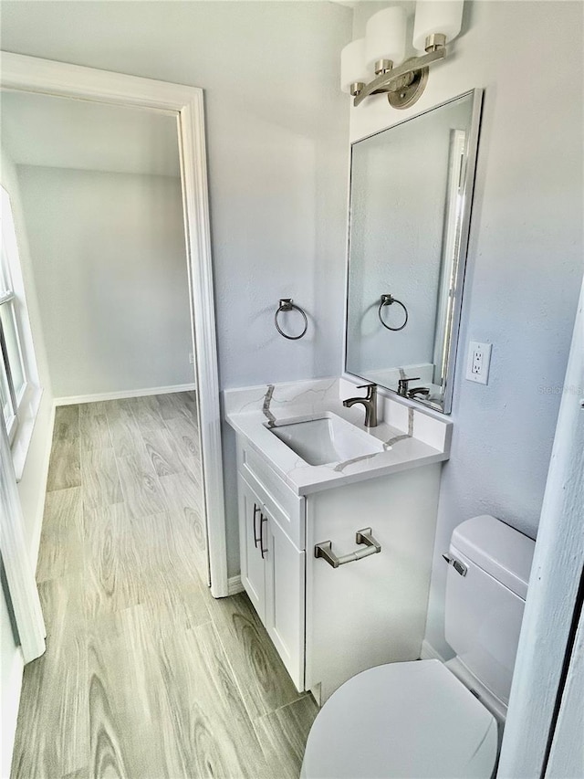 bathroom with baseboards, vanity, toilet, and wood finished floors