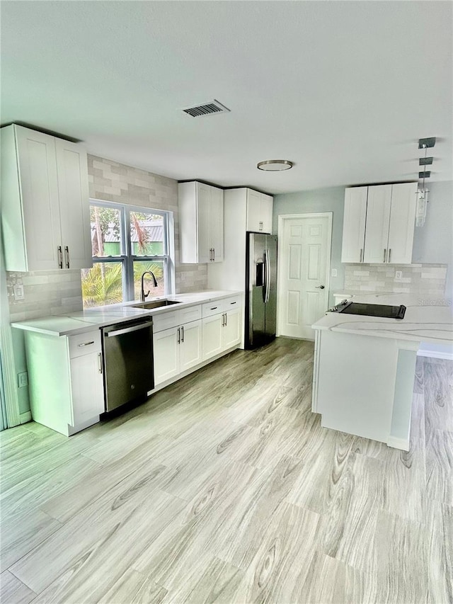 kitchen featuring dishwashing machine, stainless steel fridge, white cabinetry, and light countertops