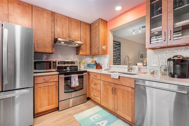 kitchen featuring appliances with stainless steel finishes, light hardwood / wood-style flooring, tasteful backsplash, and sink