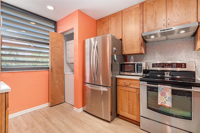 kitchen featuring backsplash, stacked washing maching and dryer, light hardwood / wood-style flooring, and stainless steel appliances