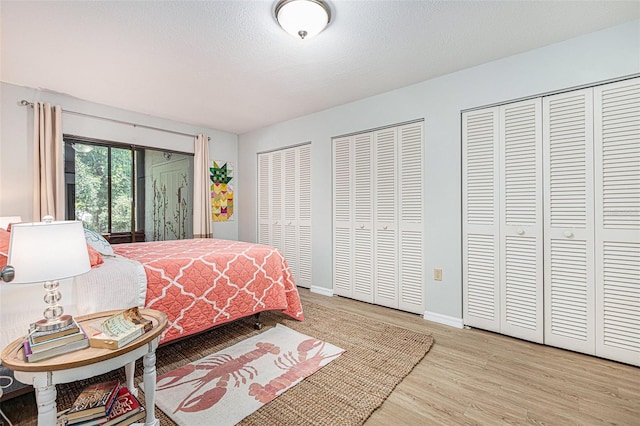 bedroom featuring a textured ceiling, light hardwood / wood-style floors, and two closets