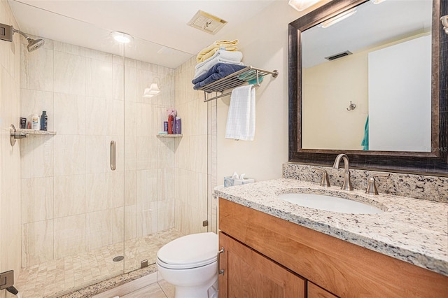 bathroom with toilet, vanity, tile patterned flooring, and a shower with door