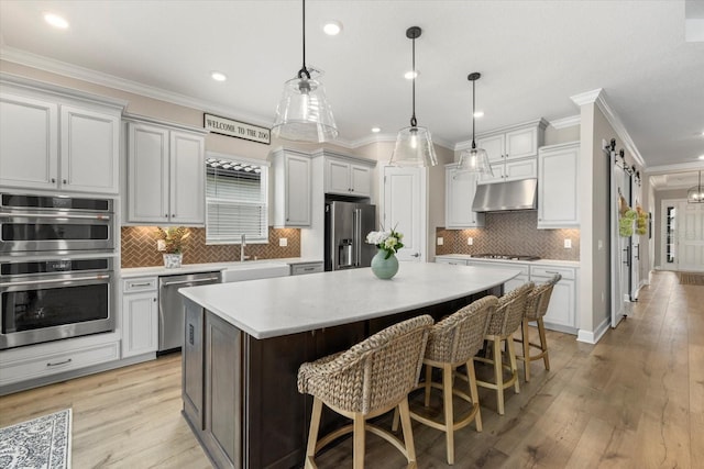 kitchen with pendant lighting, decorative backsplash, appliances with stainless steel finishes, a kitchen island, and a breakfast bar area