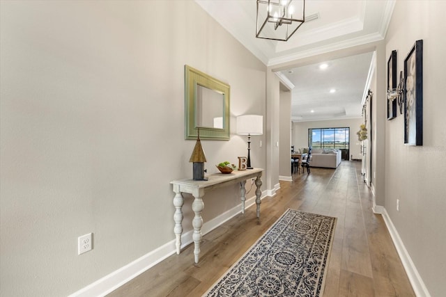 hall featuring hardwood / wood-style flooring, an inviting chandelier, and ornamental molding