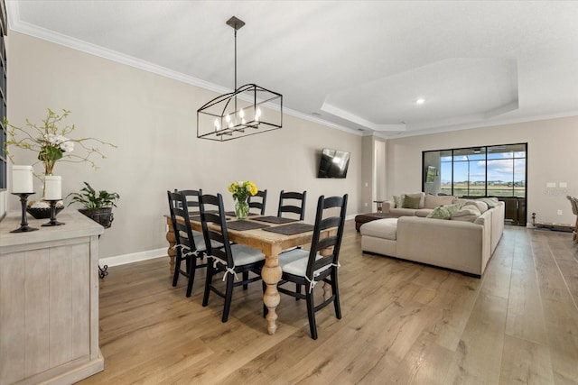 dining area with a tray ceiling, light hardwood / wood-style flooring, and crown molding